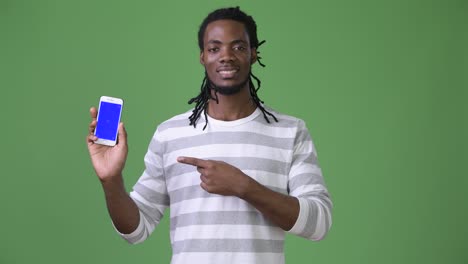 young handsome african man with dreadlocks against green background