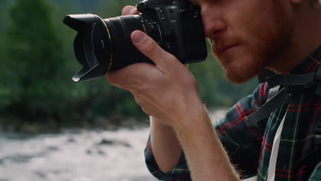 Serious-man-adjusting-zoom-on-camera-lens.-Photographer-taking-photos-on-camera