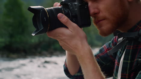 serious man adjusting zoom on camera lens. photographer taking photos on camera