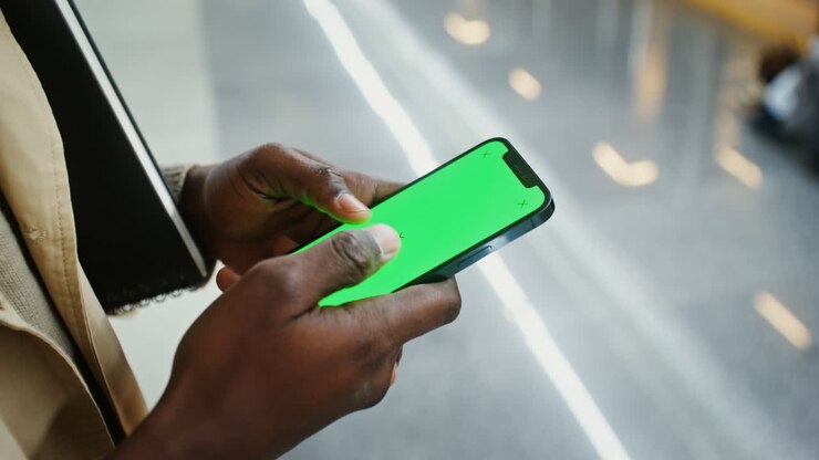 Person using a mobile phone with a green screen