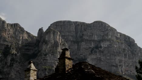 a traditional stone roof in papigo village in greece with tymfi mountain in the background