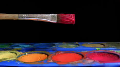el artista sumerge el pincel en rojo