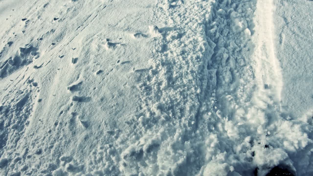 View from above of a snowboard breaking through the snow