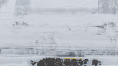 static shot of snow plow moving through snow covered roads for clearing during blizzard.
