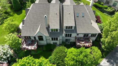 Drone-view-tilting-down-towards-a-multi-story-townhouse-with-beautiful-landscaping-and-decks-on-the-rear-of-the-building