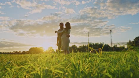 pregnant couple enjoying sunset in a field