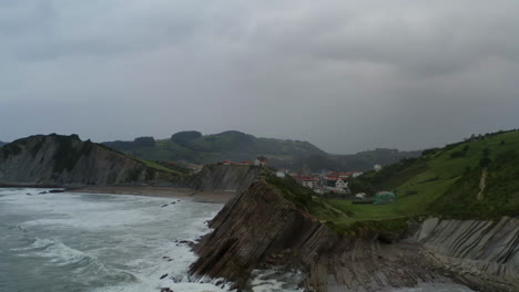 Aerial-panoramic-view-of-sea-cliffs-falling-into-ocean-at-itzurun-beach-zumaia-spain