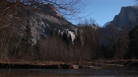 Ein-Blick-Auf-Kahlen-Bäume-Und-Felsen-Mit-Einem-Bach,-Der-Durch-Den-Vordergrund-Rauscht