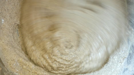 Close-up-stirring-and-mixing-a-thick-whole-wheat-batter-in-a-large-metal-bowl-with-a-whisk-for-baking