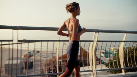 a girl in a sports uniform runs along a lattice fence on the beach. morning run on the beach