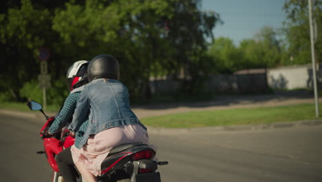 dos mujeres montando una bicicleta eléctrica, con el jinete desacelerando debido al tráfico, el botón del jinete está abierto, revelando su sello, y su amiga se aferra por detrás, los coches se pueden ver delante en el tráfico