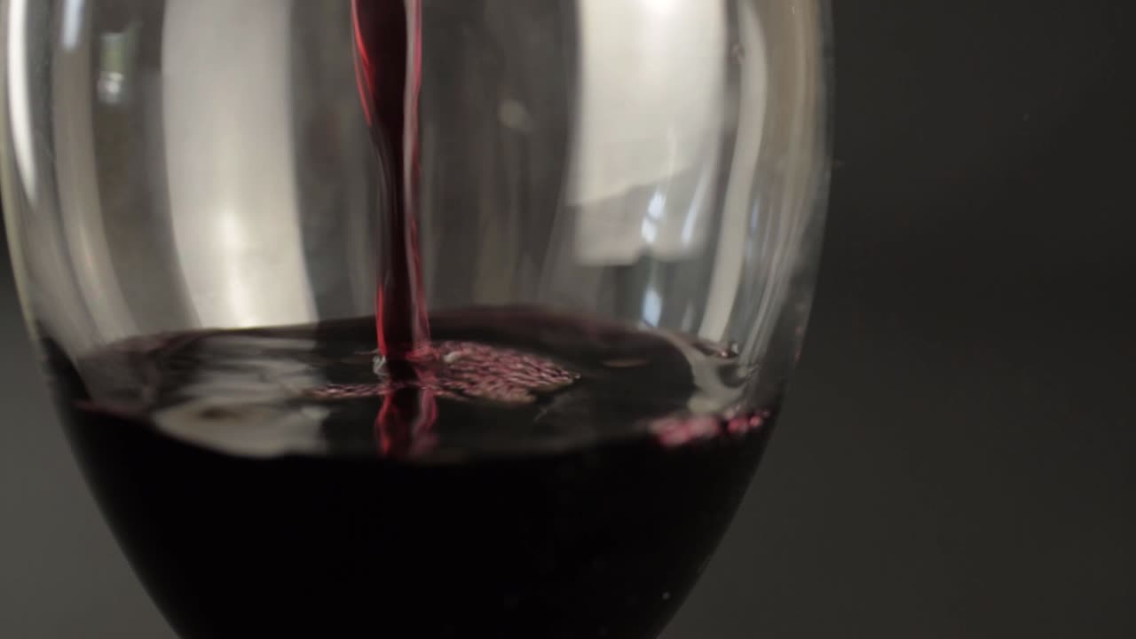 Versamento di vino rosso in un bicchiere, primo piano.