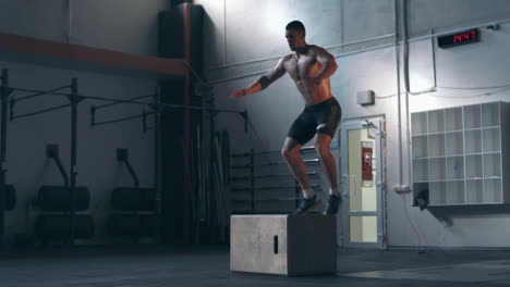 man performing box jump exercise in a gym