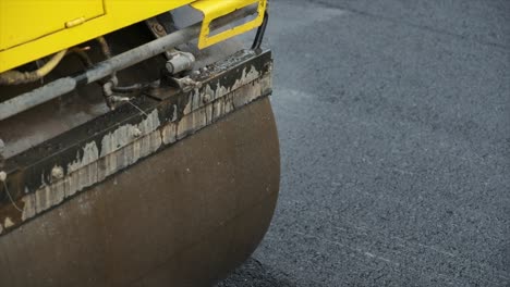 process of asphalting road construction infrastructure by compressing, compacting, leveling and smoothing the asphalt road surface using a tandem roller