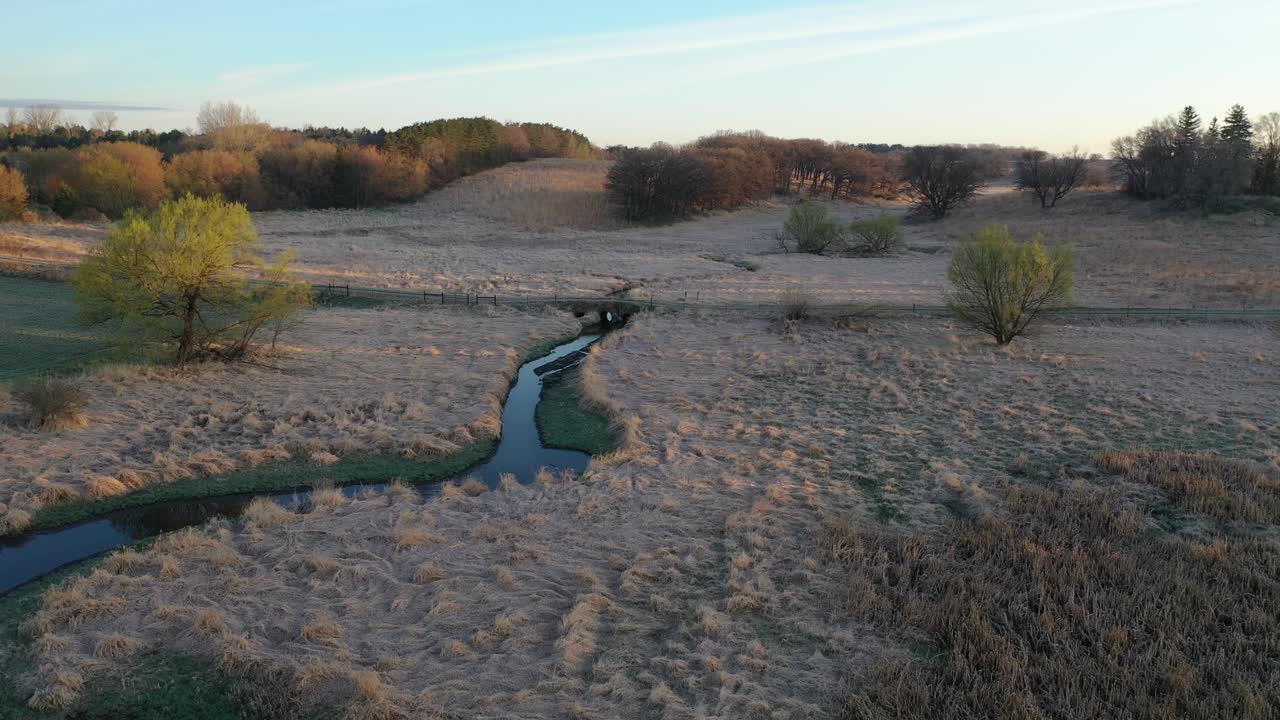 paisaje rural al amanecer con arroyo y árboles