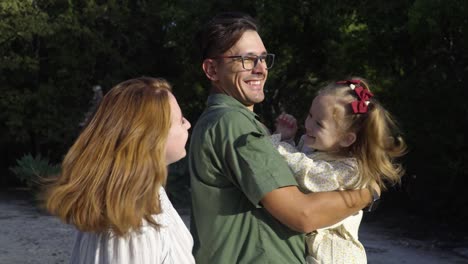 unos jóvenes padres felices están jugando con su adorable hija en el parque de la ciudad.