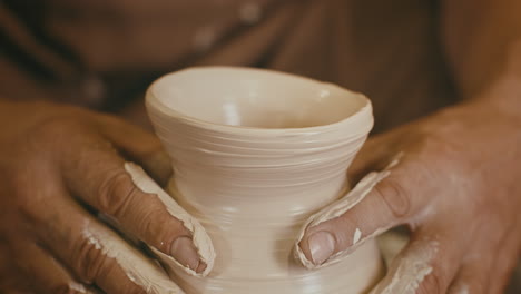 closeup of a potter shaping clay on a pottery wheel