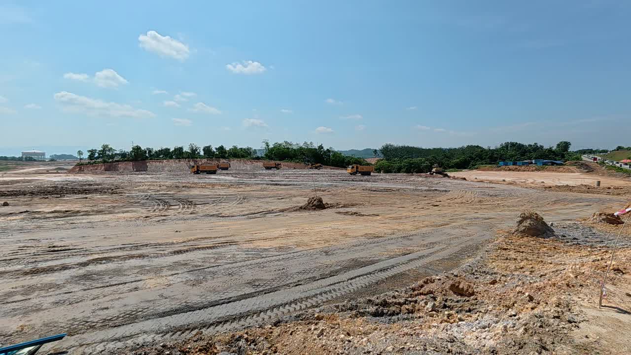 Extensive earthworks at a large construction site. Heavy machinery is used to level the ground, cutting into hills and filling in ravines to prepare the land for building new homes