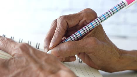 persona de edad avanzada escribiendo en un cuaderno