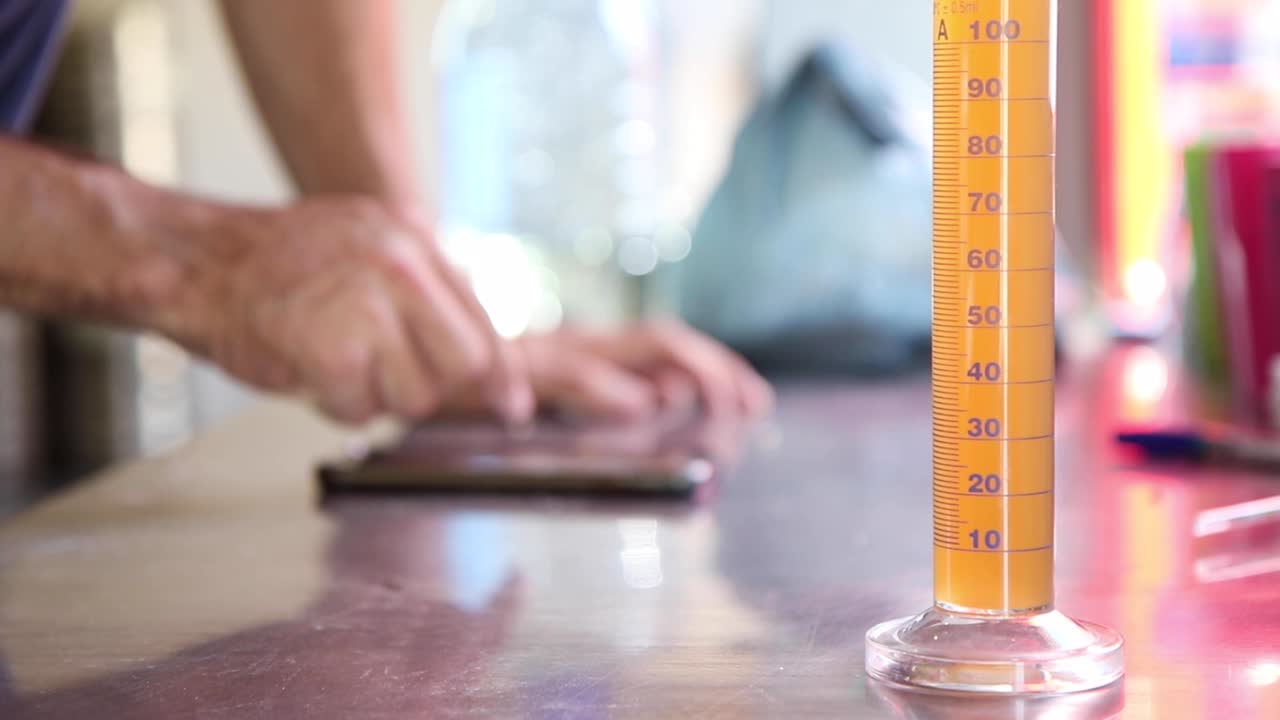 사람이 백그라운드에서 계산을 수행하는 동안 내부에 액체가 있는 테이블에 있는 테스트 튜브의 샷을 닫습니다.