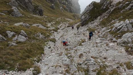 four hikers hiking in resegone rocky mountain in northern italy with clouds in background