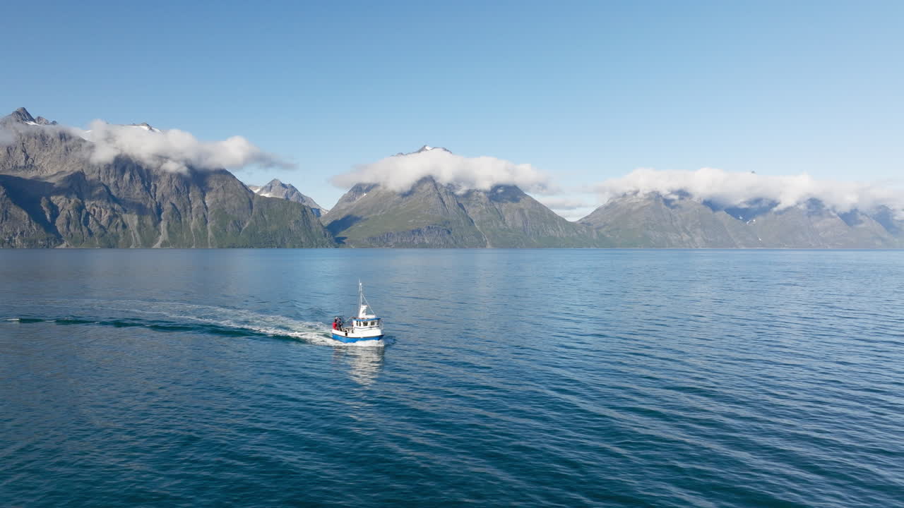 화창한 날, 노르웨이를 배경으로 링겐 알프스의 록키 산맥을 배경으로 링겐 피요르드에서 항해하는 어선에 탑승한 사람들