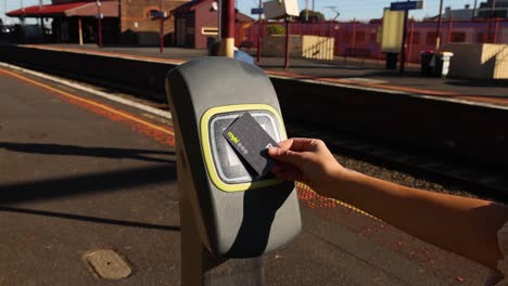 person tapping card on train station reader