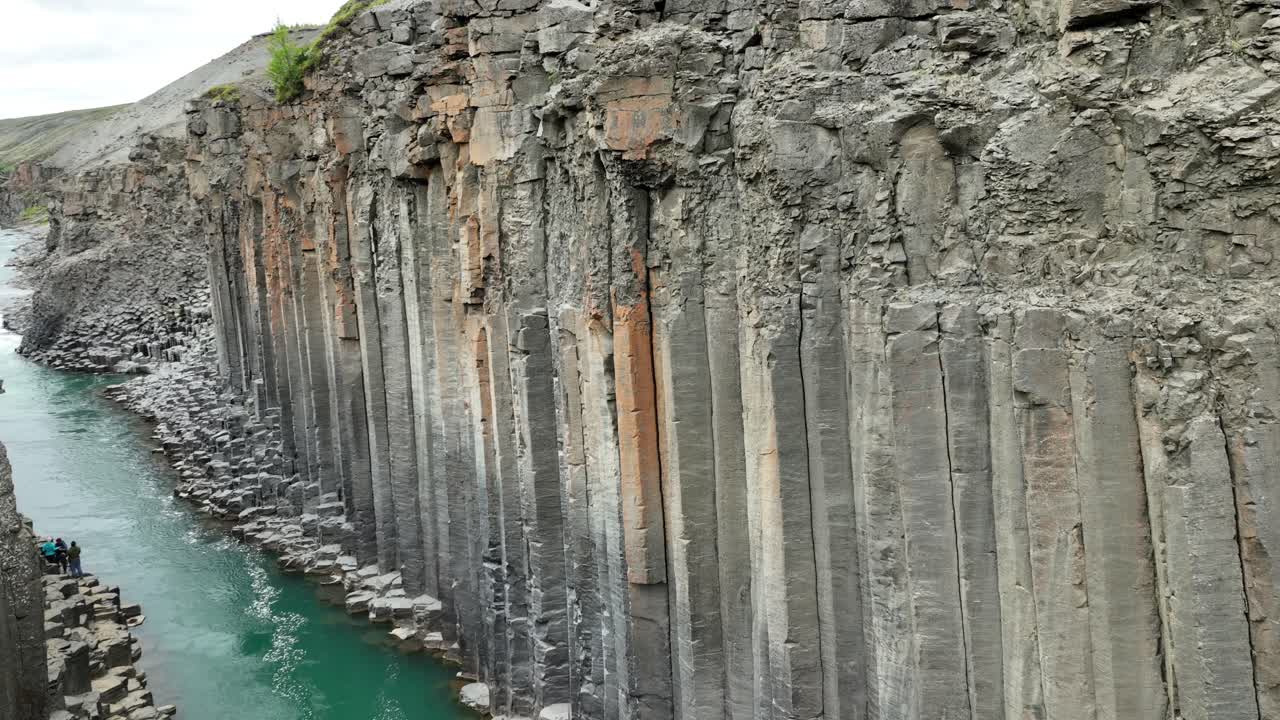 Aerial view of rocky Studlagil Canyon formation with flowing river. Iceland, Europe. Wide shot. Basalt columns and glacial blue river