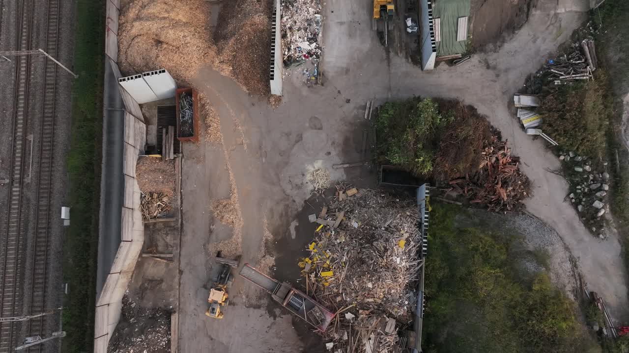 vista aérea de arriba hacia abajo de una máquina que carga materiales de madera reciclados, mostrando la eficiencia industrial, las prácticas sostenibles y el proceso dinámico de manipulación de materiales en un sitio de reciclaje.