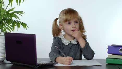 preschool child girl distance online learning at home. kid studying using digital laptop computer