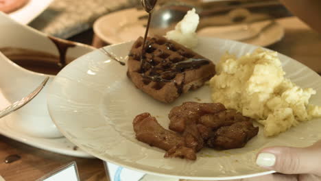 adding some chocolate syrup to a waffle