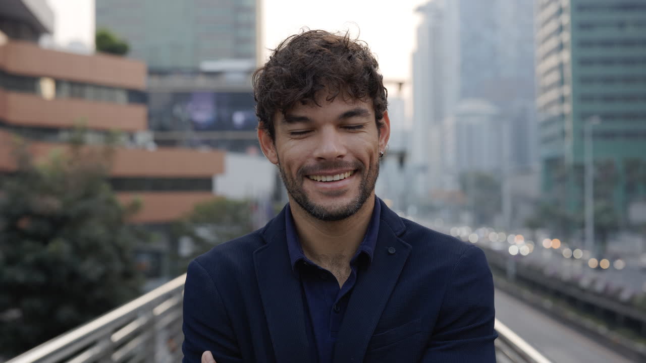 Giovane uomo sorridente e sicuro di sé che incrocia le braccia in un contesto urbano