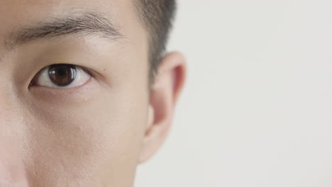 Nahaufnahme-Eines-Jungen-Asiatischen-Mannes,-Der-Die-Augen-öffnet-Und-Auf-Einen-Kopierraum-Mit-Weißem-Hintergrund-Blickt