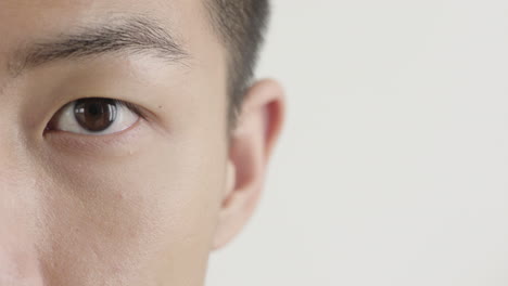 close up young asian man eye opening looking on white background copy space