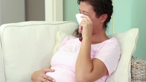 mujer embarazada llorando en el sofá