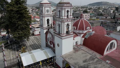 Beautiful-aerial-cinematic-view-of-white-cross-on-top-of-white-church-with-red-roof