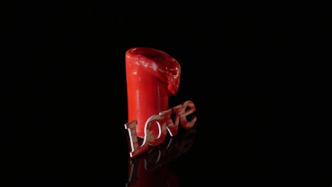 a single burning red candle rotate isolated in front of black background