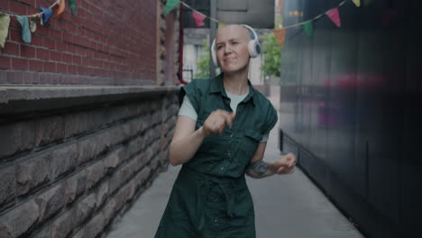 woman dancing in an urban alleyway with headphones