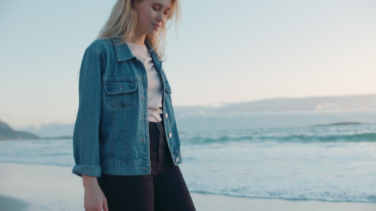 mujer joven caminando descalza por la playa al atardecer contemplando el viaje disfrutando de la tranquila orilla del mar mirando el océano con los brazos levantados sintiéndose feliz