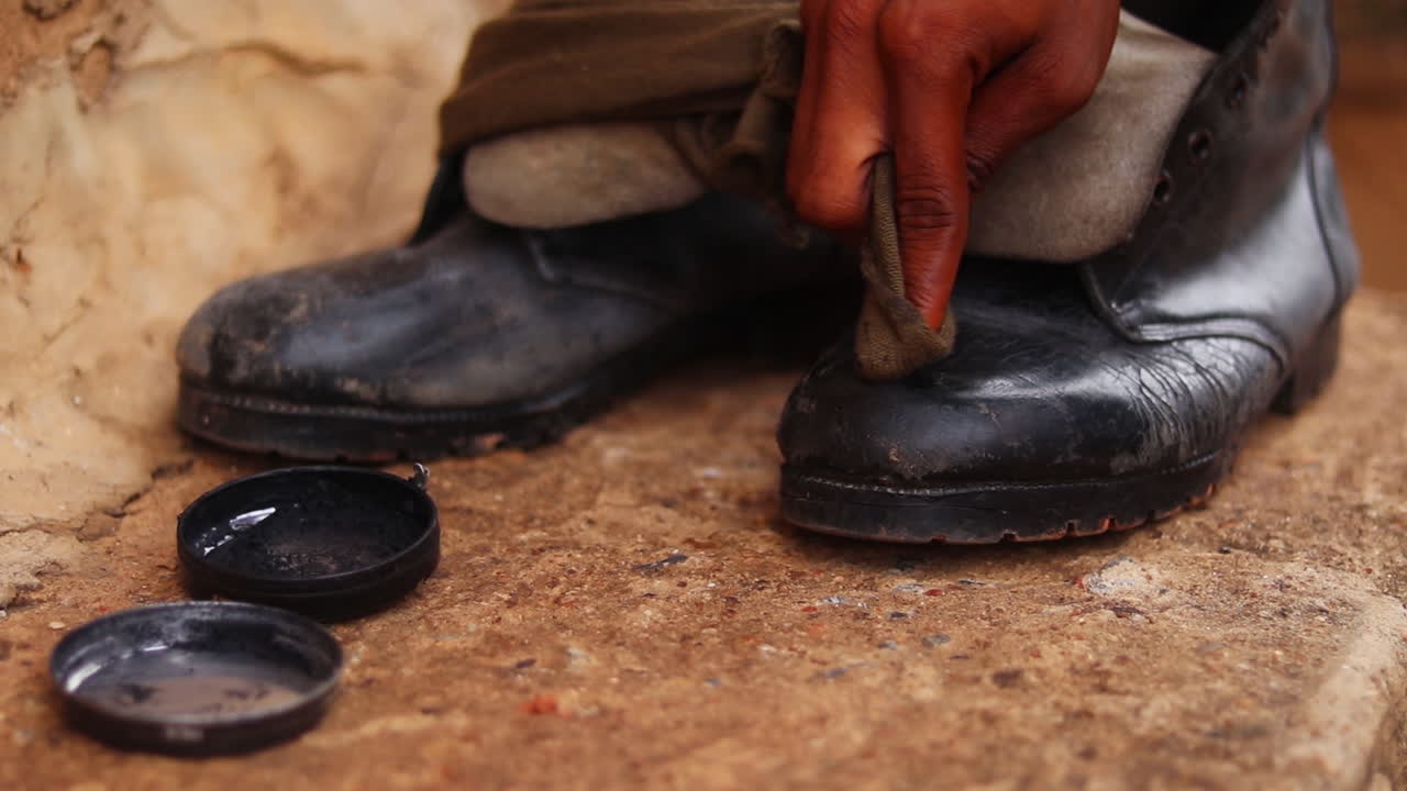 Close up hand polishing black boots and shining the nose of the shoe