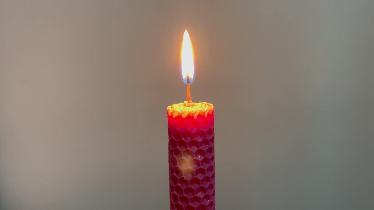 Hořící červená voštinová svíčka