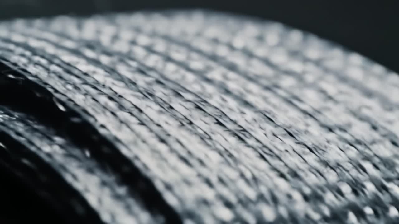 Close-Up of Textured Metallic Surface Showcasing Intricate Weaving and Reflective Qualities in a Dark Background