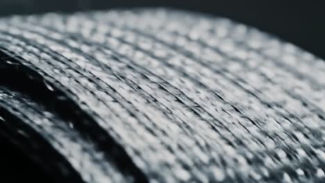 close-up of textured metallic surface showcasing intricate weaving and reflective qualities in a dark background