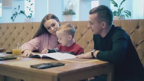 boy kid sits between mother and father in restaurant