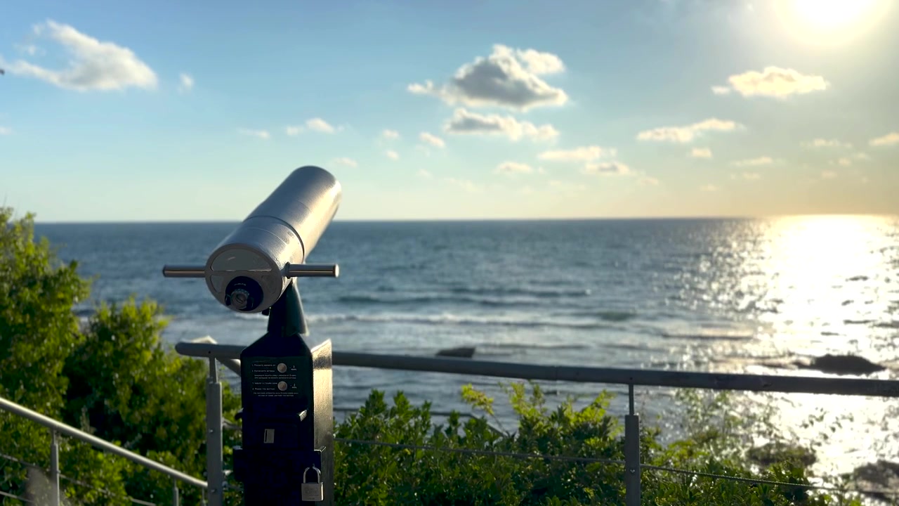 Dalekohledy s výhledem na moře při východu slunce, panoramatický výhled na oceánský horizont z prázdné pobřežní vyhlídkové plošiny, klidná zlatá ranní krajina. Scéna E.