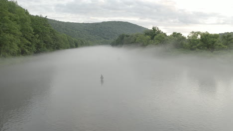 drone fly by footage of fly fishing in foggy weather