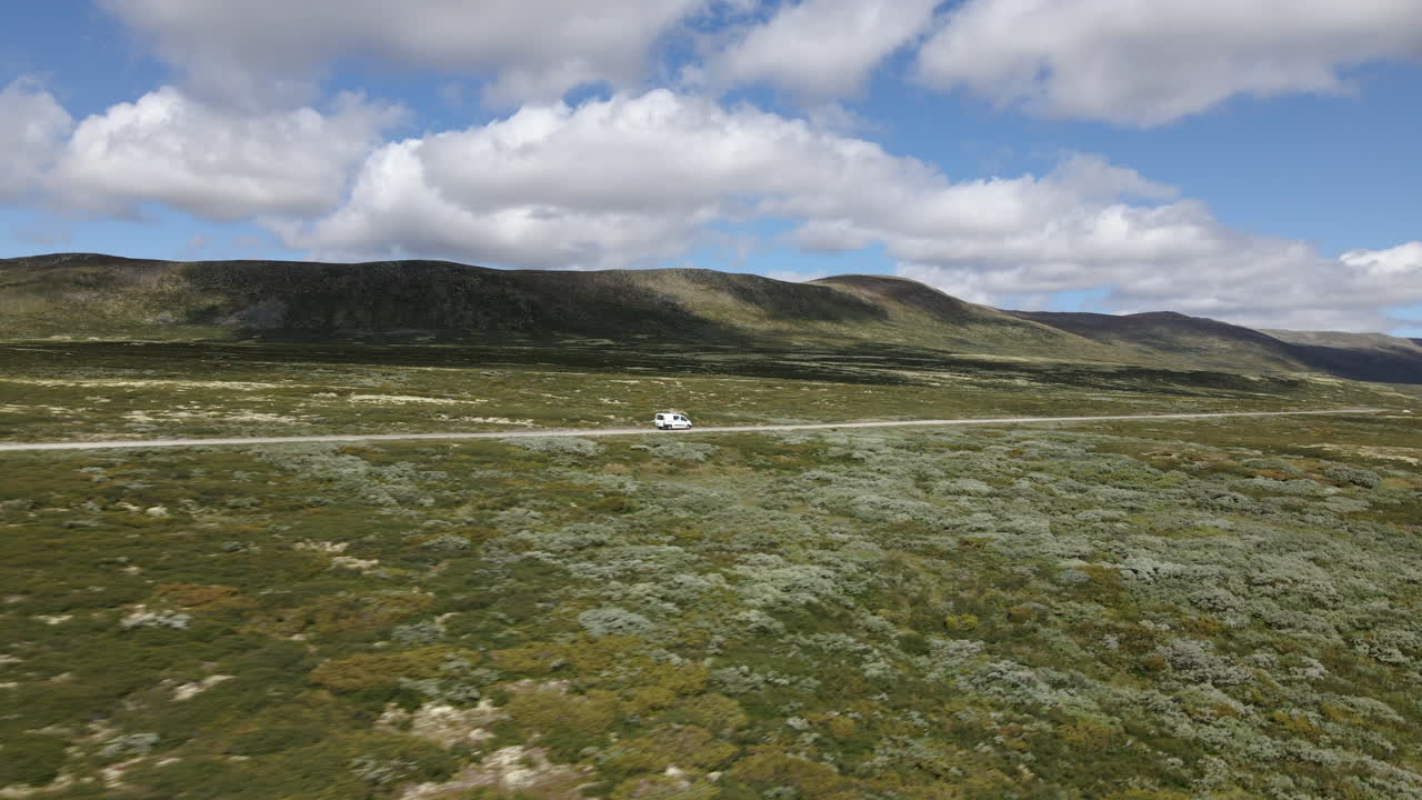 toma aérea de un camión moviéndose en el día soleado con una montaña al fondo