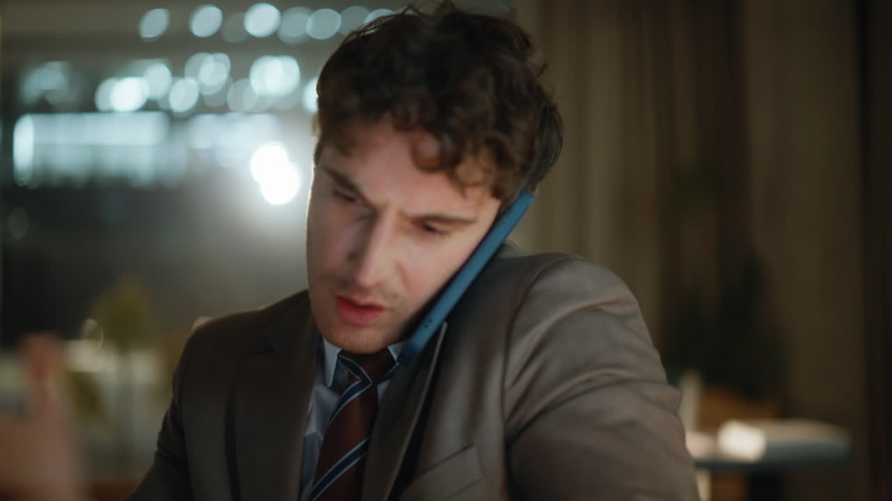 Emotional man calling late evening office sitting laptop workplace portrait