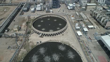 aerial footage of a large scale oil refinery with smoke stacks and petroleum storage tanks
