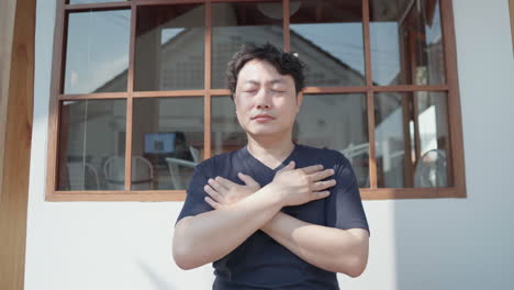 close up of asian man do breathing exercise with hands to chest to practice mindful yoga